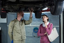 Mechanic and customer under car