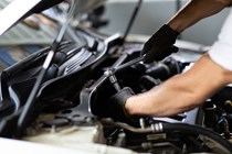 Image of a mechanic undoing a bolt on a car's engine