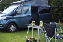 The two Ryobi camping tools near a campervan