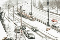 Image of cars driving and parked on adjacent roads in a heavy snow storm