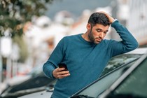Man with phone at car dealer - How to spot a clocked car