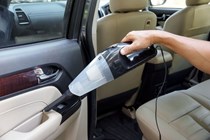 A handheld vacuum cleaner being used to clean a car door