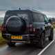 Land Rover Defender 130 V8 review: rear three quarter driving, British B-road, low angle, black paint