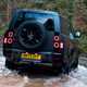 Land Rover Defender 130 V8 review: rear three quarter off-roading, fording a stream, black paint