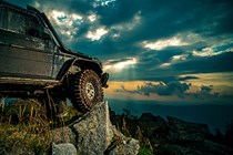 Four wheel drive vehicle parked on a rock peak looking over a sunset vista