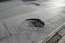How to claim for pothole damage in the UK - road with two large potholes