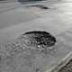 How to claim for pothole damage in the UK - road with two large potholes