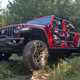 Jeep Gladiator review - red, tube doors, front view driving off-road over bumps