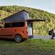 Ford Transit Custom Nugget campervan - rear view, orange, parked by lake with tailgate open