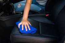 A leather seat being cleaned with a microfibre towel