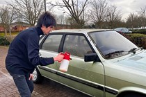 Aaron Hussain applies a pre-wash to the car using a pump sprayer.