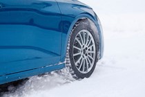 A closeup of a car's wheel being driven on snow
