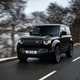 A black Land Rover Defender 90 driving on wintery roads. Our best small luxury car for adventure.