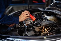 A mechanic using a torch in an engine bay
