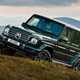 Best luxury SUVs - Mercedes-Benz G-Class, front view, green, parked half way up grassy hill and jaunty angle