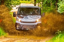 Iveco Daily 4x4 Off-Road chassis cab, white, front view, making a big splash through muddy water