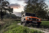 Ineos Grenadier 4x4 - front view, prototype, silver and orange, driving at sunset