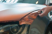 Copper coloured wrap being applied to the bonnet of a car