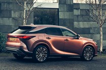 Lexus RX 450h+ (2023) review: rear three quarter static, bronze car, house in background