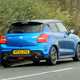 Suzuki Swift Sport (2023) review: rear three quarter driving, blue car, British B-road