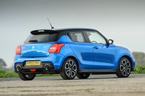 Suzuki Swift Sport (2023) review: rear three quarter static, blue car, wood in background
