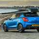 Suzuki Swift Sport (2023) review: rear three quarter static, blue car, beach background