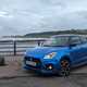 Suzuki Swift Sport long termer front three quarter, parked by the shore