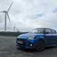 Suzuki Swift Sport long termer front three quarter, parked in front of some windmills