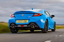 Toyota GR86 review: rear three quarter tracking driving, low angle, country road, blue paint