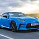 Toyota GR86 review: front three quarter tracking driving, country road, blue paint
