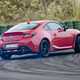 Toyota GR86 review: rear three quarter track driving, doing a massive skid, high angle, red paint