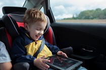 Child in car seat with tablet