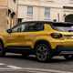 Jeep Avenger (2023) review: rear three quarter driving, yellow paint, town background