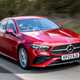 Mercedes A-Class Saloon, front three quarter tracking, high angle, red paint, wooded background