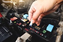 Image of a man's hand removing fuse from a car fuse box
