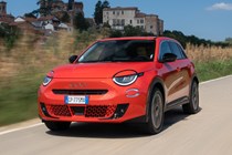 Fiat 600e front three quarter driving, orange paint, Italian roads