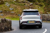 Kia EV9 review (2024): rear three quarter cornering, silver paint, British country road, on chicane
