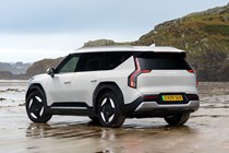 Kia EV9 review (2024): rear three quarter static, silver paint, parked on a beach