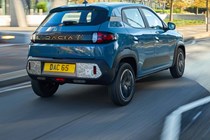 Dacia Spring review - rear view, blue, driving in the UK