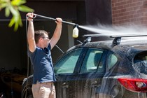 Man washing car with compact pressure washer