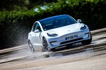 Most efficient electric cars: Tesla Model 3, front three quarter driving, powersliding around a wet skid pan, white paint