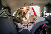 Woman belting baby into car - How to choose a baby car seat