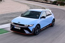 Hyundai Ioniq 5 N (2024) review: front three quarter driving, on track, high angle, matte blue paint, Spanish roads