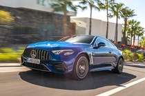 Mercedes-AMG CLE 53 review: front three quarter driving, low angle, building trees in the background, blue paint