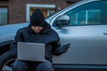 Thief with laptop beside car