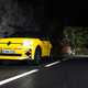 Renault 5 E-Tech (2024) review: front three quarter driving, low angle, yellow paint, through cave