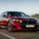 BMW i5 Touring: M60 model, front three quarter driving, sunset, red paint