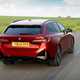 BMW i5 Touring: M60 model, rear three quarter driving, red paint