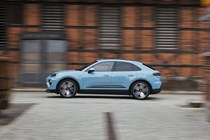 Porsche Macan Electric (2024) review: side view driving, blue paint, past buildings