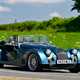 Morgan Plus Six review - front, blue, driving round corner in British sunshine, exclusive Bauer image